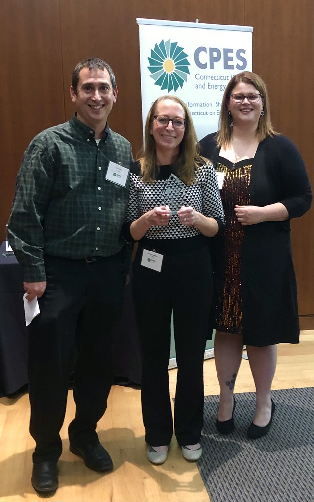 Three people standing together, accepting an award