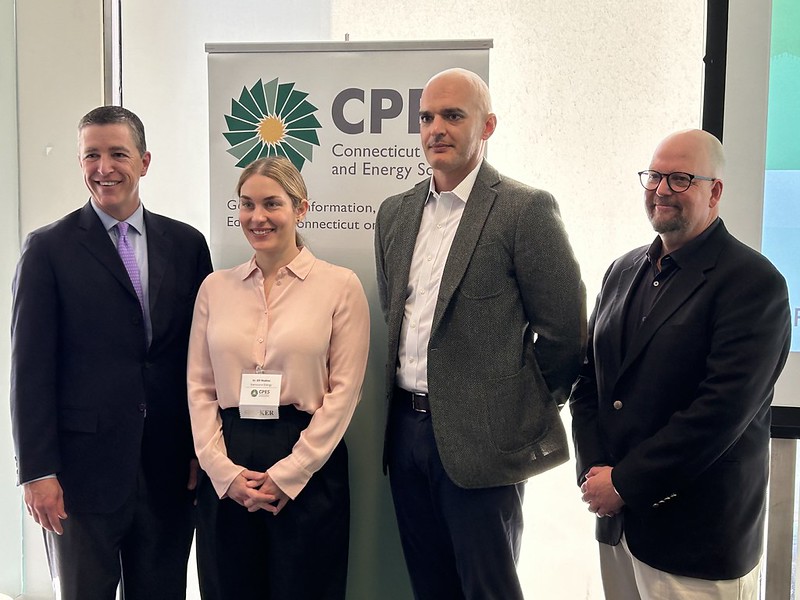 Four professionals standing in front of the CPES sign at their conference